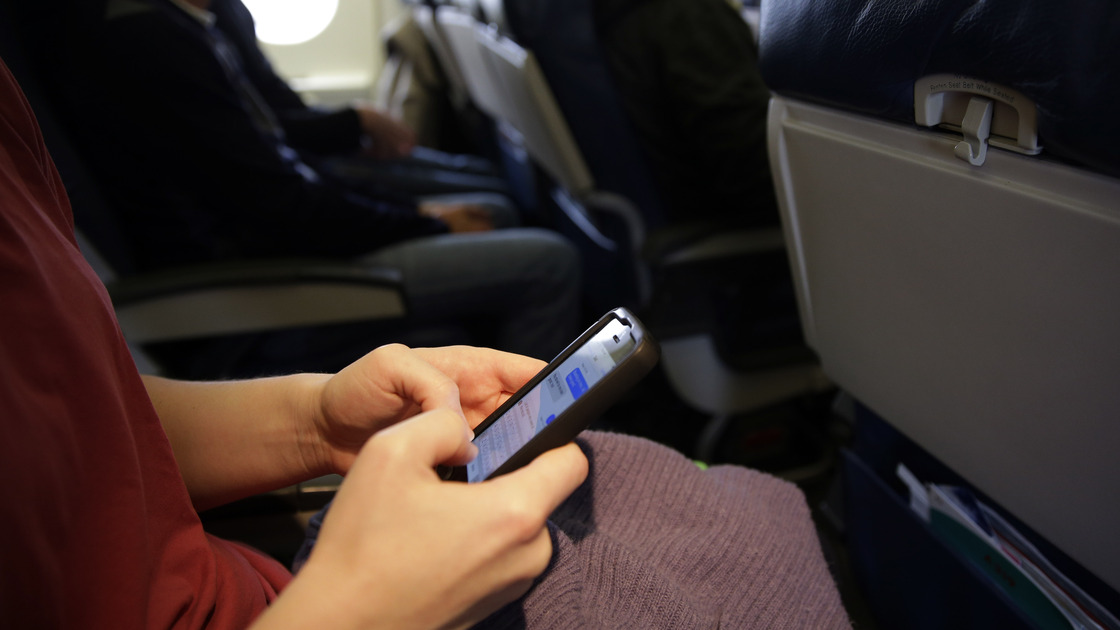 The new head of the Federal Communications Commission proposes allowing airline passengers to make phone calls during flights. Here, a passenger looks at her cellphone before a flight last month.
