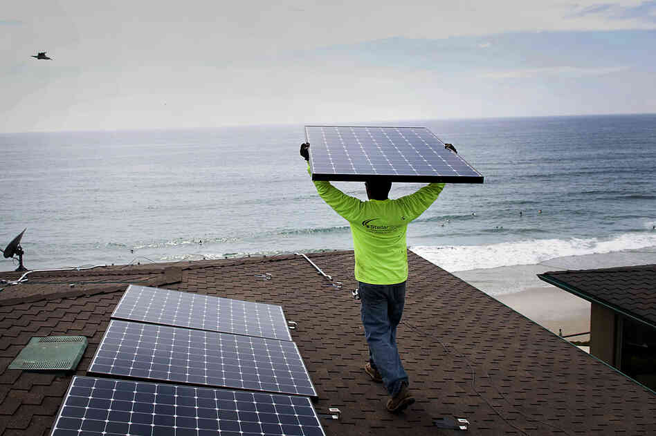 Andres Quiroz, an installer for Stellar Solar, carries a solar panel during installation at a home in Encinitas, Calif. Andres Quiroz, an installer for Stellar Solar, carries a solar panel during installation at a home in Encinitas, Calif.