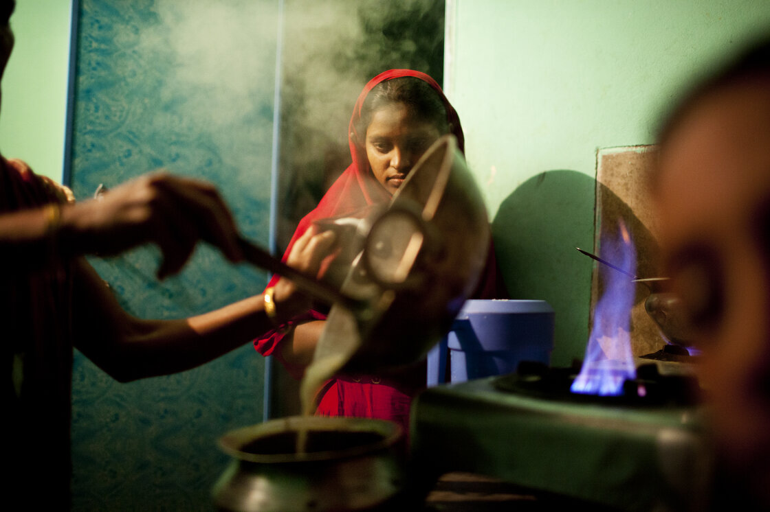 Minu cooks on the two shared burners outside the sisters' room in Chittagong. Minu cooks on the two shared burners outside the sisters' room in Chittagong.