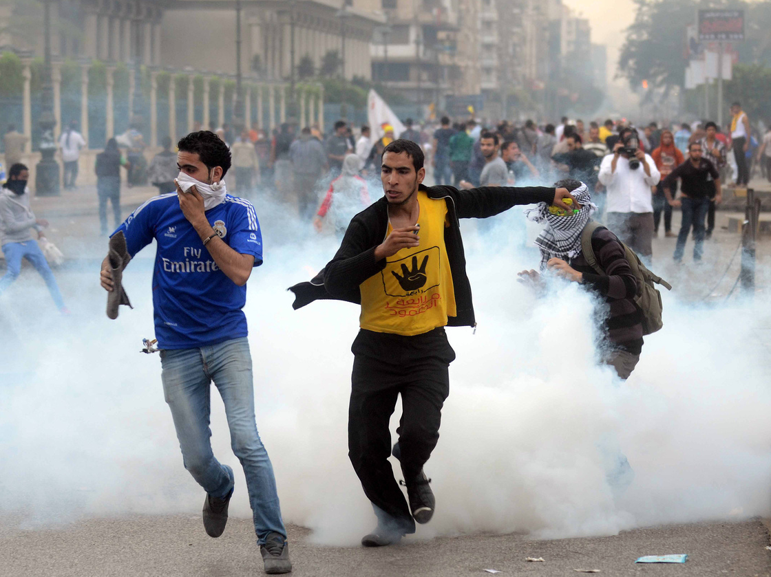 Supporters of the Muslim Brotherhood run from tear gas during clashes with riot police close to Cairo