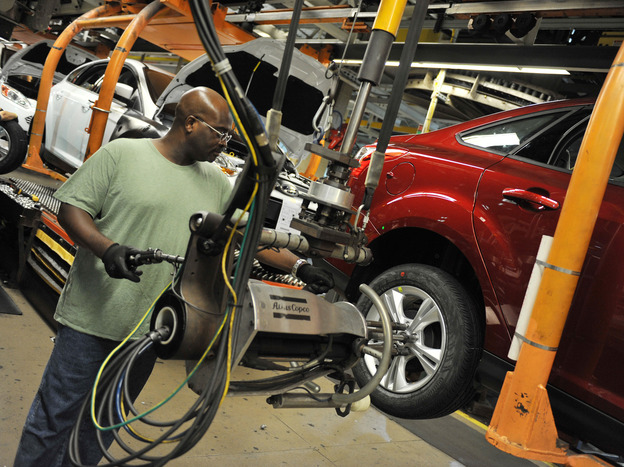 An auto worker tightens bolts on the wheel of a Focus at a Ford plant in Wayne, Mich. Reports this week showed increases in auto sales and manufacturing jobs. (Image credit: AFP/Getty Images)