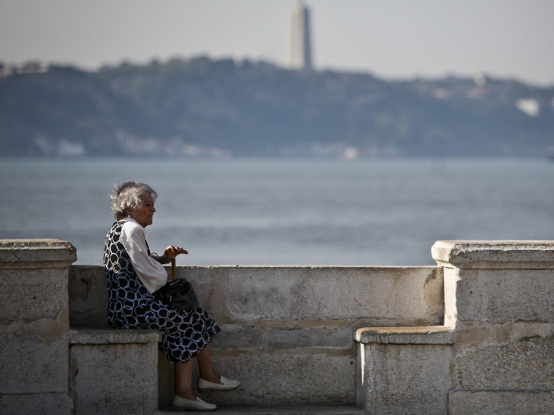 An elderly woman sits near the Tejo River in Lisbon on Oct. 17, 2011. Portugal