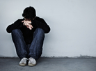A young man looking sad while sitting on the ground with his head on his hands A young man looking sad while sitting on the ground with his head on his hands