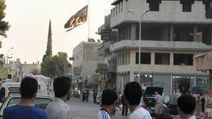 Men look at a jihadist flag flying over Raqqa on Sept. 28, 2013.