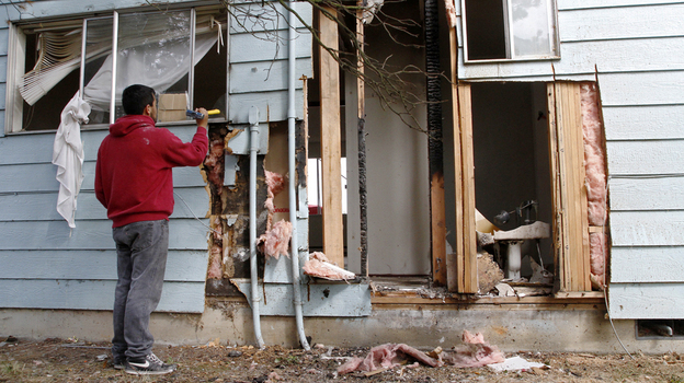 Rodrigo Fernandez, neighbor in an adjacent apartment complex, helps clean up after an explosion in Mount Vernon, Wash., in August. Police say it was likely caused when people extracted hash from a marijuana plant by mixing parts of it with butane in a two-liter pop bottle. (Image credit: The Skagit Valley Herald)