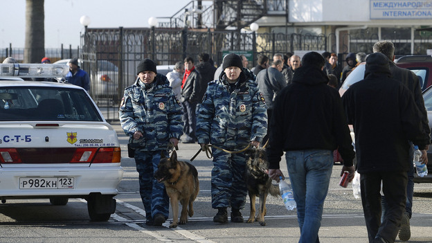 Police officers with dogs walk along a street in Sochi, Russia, on Jan. 6. The presence of security personnel has ramped up recently ahead of the Winter Olympics. (Image credit: Kyodo /Landov)