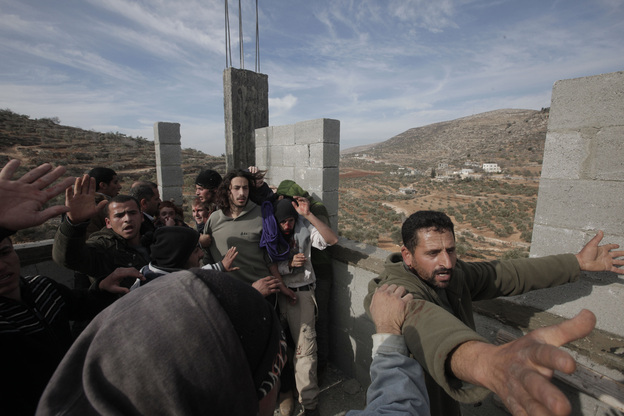 Palestinians (front and left) try to prevent fellow Palestinians from the village of Qusra from attacking a group of Israeli settlers after they sparked clashes upon entering the village near Nablus, in the Israeli-occupied West Bank, on Jan. 7. (Image credit: AFP/Getty Images)