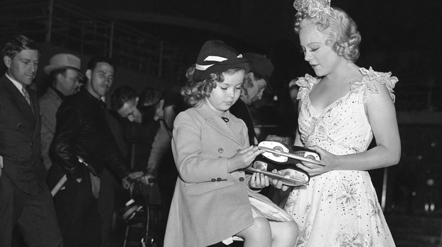 Skater Sonja Henie (right) presents Shirley Temple with a pair of skates. (AP)
