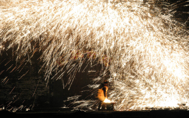 Chinese blacksmiths in Nuanquan (Warm Spring) Town perform a folk custom called 'making trees and flowers.' They throw ladles of molten iron onto a wall, creating showers of sparks. The centuries-old custom originated with blacksmiths too poor to afford fireworks. In recent years, urban tourists have flocked to this once obscure town over the Chinese New Year holiday to enjoy local folk customs. (Image credit: NPR)