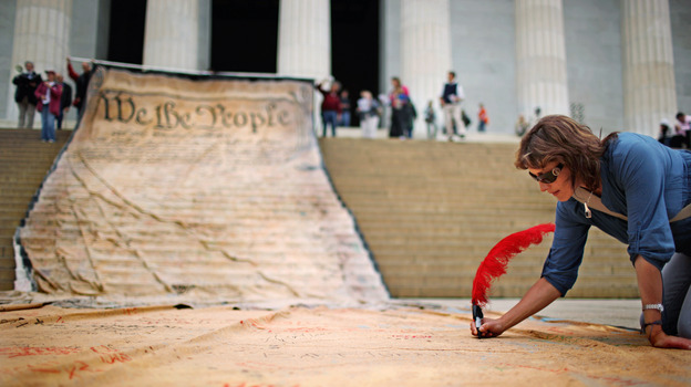 A woman signs a giant banner printed with the preamble to the U.S. Constitution during a demonstration against the Citizens United ruling in Washington in October 2010. (Image credit: Getty Images)