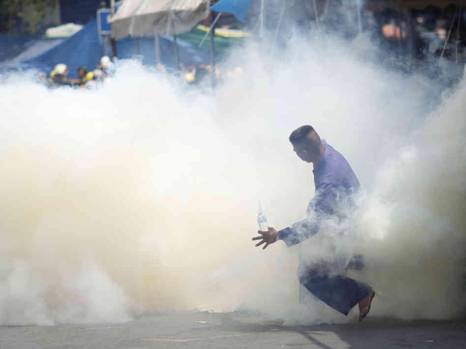 An anti-government protester is caught in tear gas during clashes with riot police in Bangkok, Thailand, on Tuesday. An anti-government protester is caught in tear gas during clashes with riot police in Bangkok, Thailand, on Tuesday.
