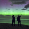 People view the Northern Lights over Bamburgh Castle Beach Thursday in Northumberland, England. A powerful solar flare caused the aurora borealis to be  visible farther south than usual.