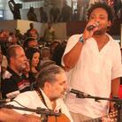 Sitting around what looks like a conference table with a small group of musicians, guitarist Moacyr Luz (center) leads his samba group. Sitting around what looks like a conference table with a small group of musicians, guitarist Moacyr Luz (center) leads his samba group.