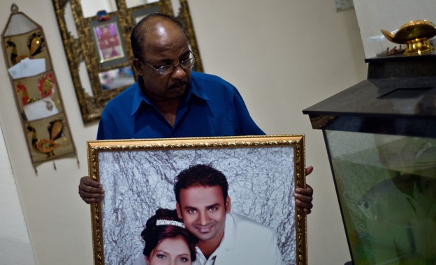 Subramaniam Gurusamy holds a portrait of his son Puspanathan, who was onboard the missing Malaysia Airlines flight, on Friday in his home in Teluk Panglima Garang, outside Kuala Lumpur. (Image credit: AFP/Getty Images)