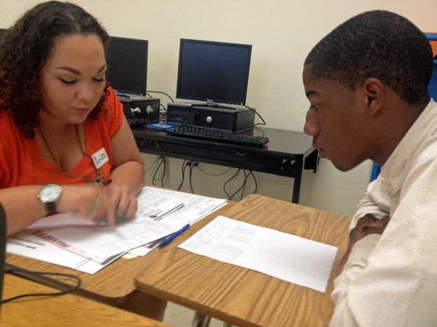 Student Mack Godbee and mentor Natasha Santana-Viera go over Godbee's report card. Godbee's performance has improved since a data monitoring program identified him as a dropout risk. (Image credit: StateImpact Florida)