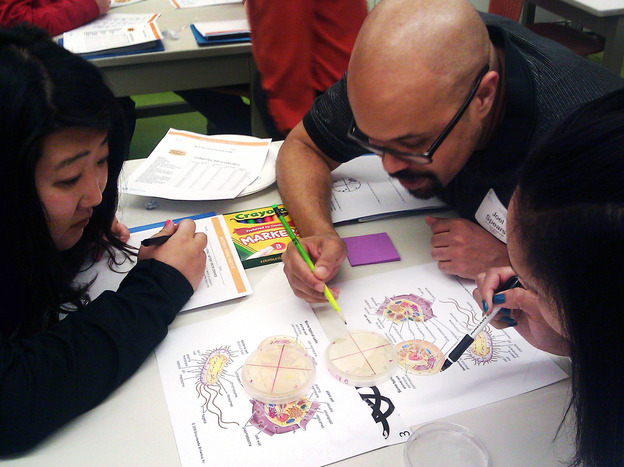 Science teachers huddle over bacteria colonies at Chicago's Museum of Science and Industry. The museum plans to train 1,000 area educators to be better science teachers in the next five years. (Image credit: WBEZ)