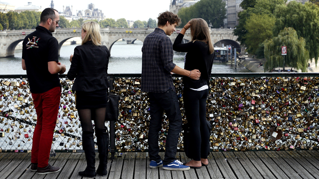 Couples stand on the Pont des Arts, Paris' iconic footbridge over the Seine river, where thousands upon thousands of padlocks bearing love messages are attached to the railing, on Aug. 30, 2013. (Image credit: AFP/Getty Images)