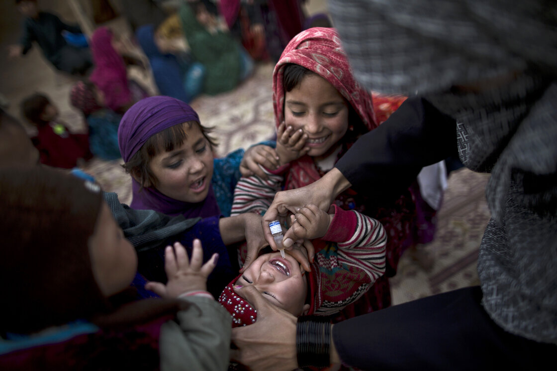 On the outskirts of Islamabad, a Pakistani health worker vaccinates an Afghan refugee against polio.