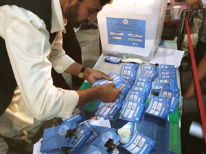 An Afghan election worker examines ballots to check for similar handwritten marks that would suggest ballot-stuffing fraud.