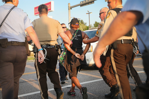 Police arrest a woman in Ferguson, Mo., protesting the shooting death of Michael Brown. Most officers in Ferguson and nearby Jennings are white, but the neighborhoods they police are predominantly African-American. (Image credit: Getty Images)