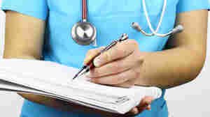A nurse writes notes on a pad of paper.