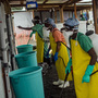 Workers wait to spray disinfectant on medical staff after they treat Ebola patients at a clinic run by Doctors Without Borders, in Monrovia, Liberia.