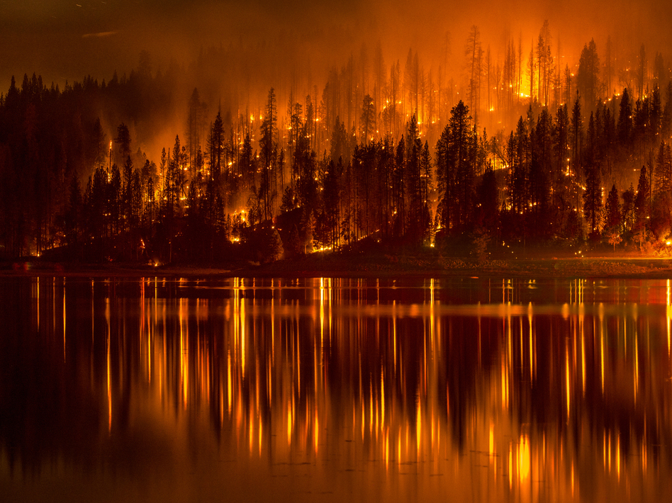 A photo from Sunday shows a wildfire as it approaches the shore of Bass Lake, Calif. Several blazes are being fueled by record drought conditions.