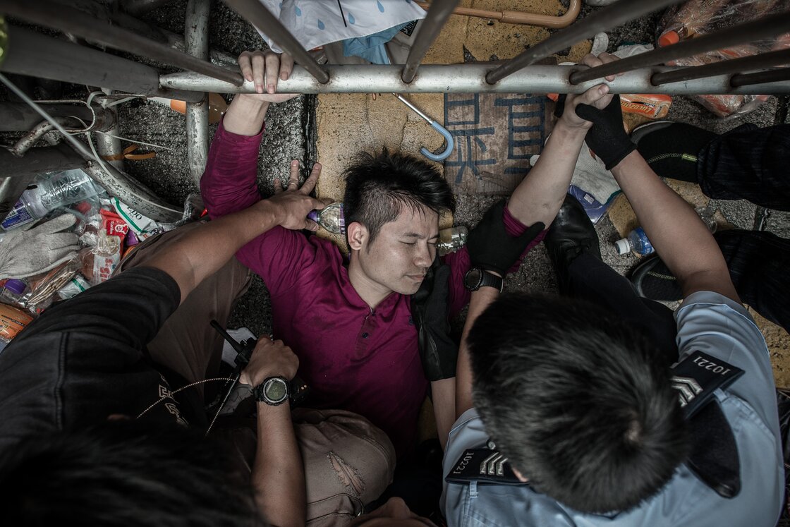 Policemen try to get a man to let go of a fence guarded by pro-democracy demonstrators. Policemen try to get a man to let go of a fence guarded by pro-democracy demonstrators.