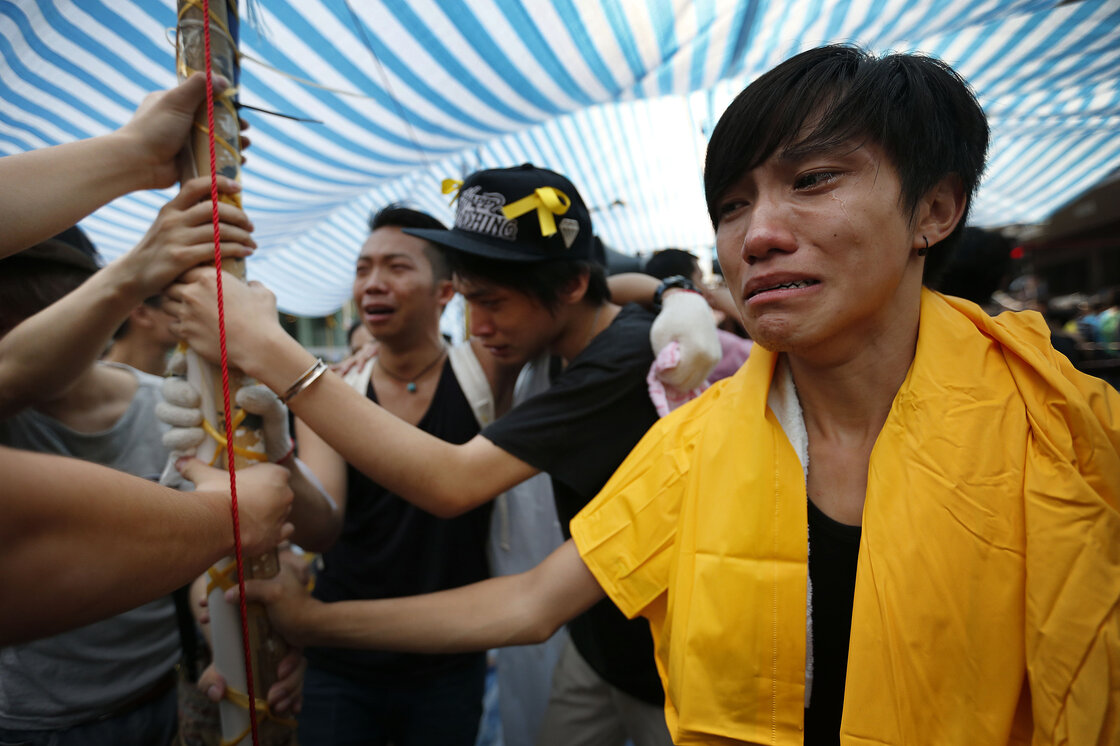 Student protesters are overwhelmed with emotions as they hold onto their tent while being threatened by residents and pro-Beijing supporters in Kowloon's crowded Mong Kok district. Student protesters are overwhelmed with emotions as they hold onto their tent while being threatened by residents and pro-Beijing supporters in Kowloon's crowded Mong Kok district.