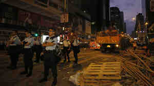 Police officers stand guard at a main street in Mong Kok district in Hong Kong on Friday, where they raided a student protest site.
