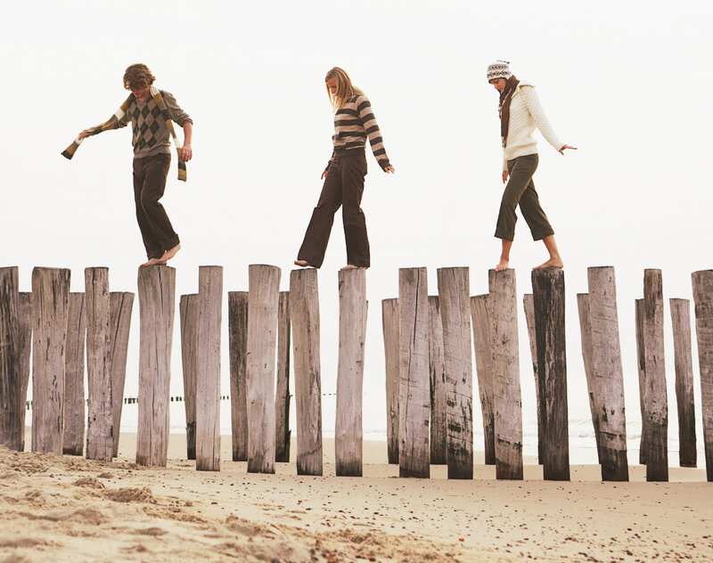 Friends balance on pilings at the beach. Friends balance on pilings at the beach.