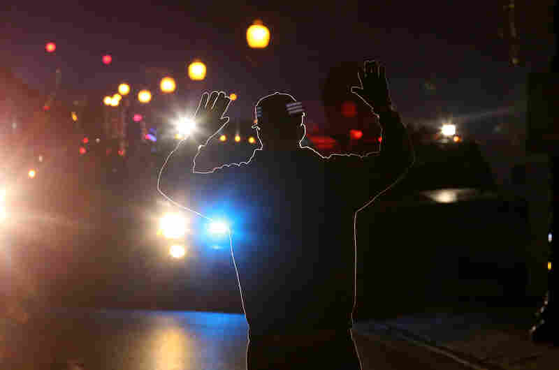 A protester stands in front of police vehicles with his hands up during a demonstration in Ferguson. More than 80 people were arrested in the St. Louis area.