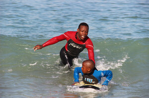 Lwandile Mntanywa helps a younger surfer learn to catch a wave. He's a "junior leader" in the Waves for Change program. Lwandile Mntanywa helps a younger surfer learn to catch a wave. He's a "junior leader" in the Waves for Change program.