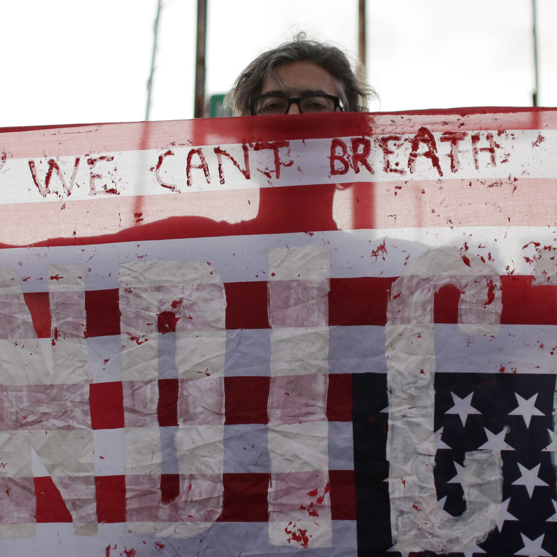 A protester holds an American flag with the word "Indict" painted on it Friday during a protest in Miami.
