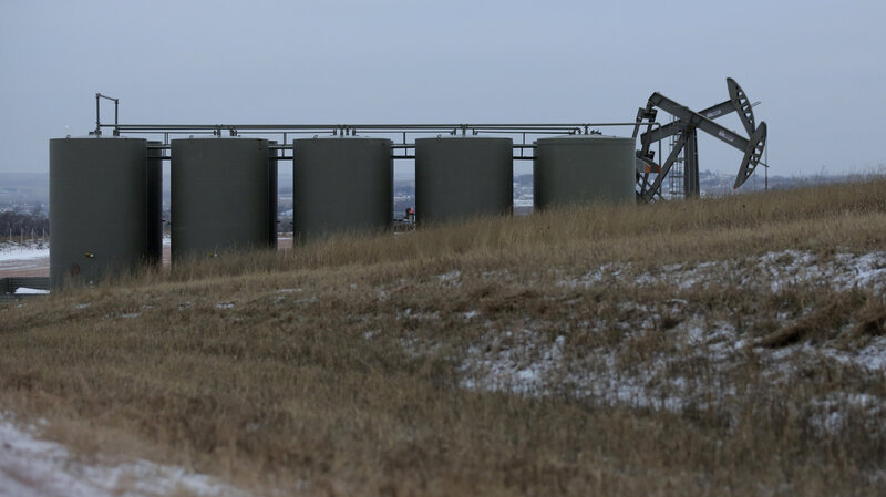 Oil pump jacks and storage tanks are seen Dec. 17 near Watford City, N.D. Oil prices are half what they were at the start of the year.