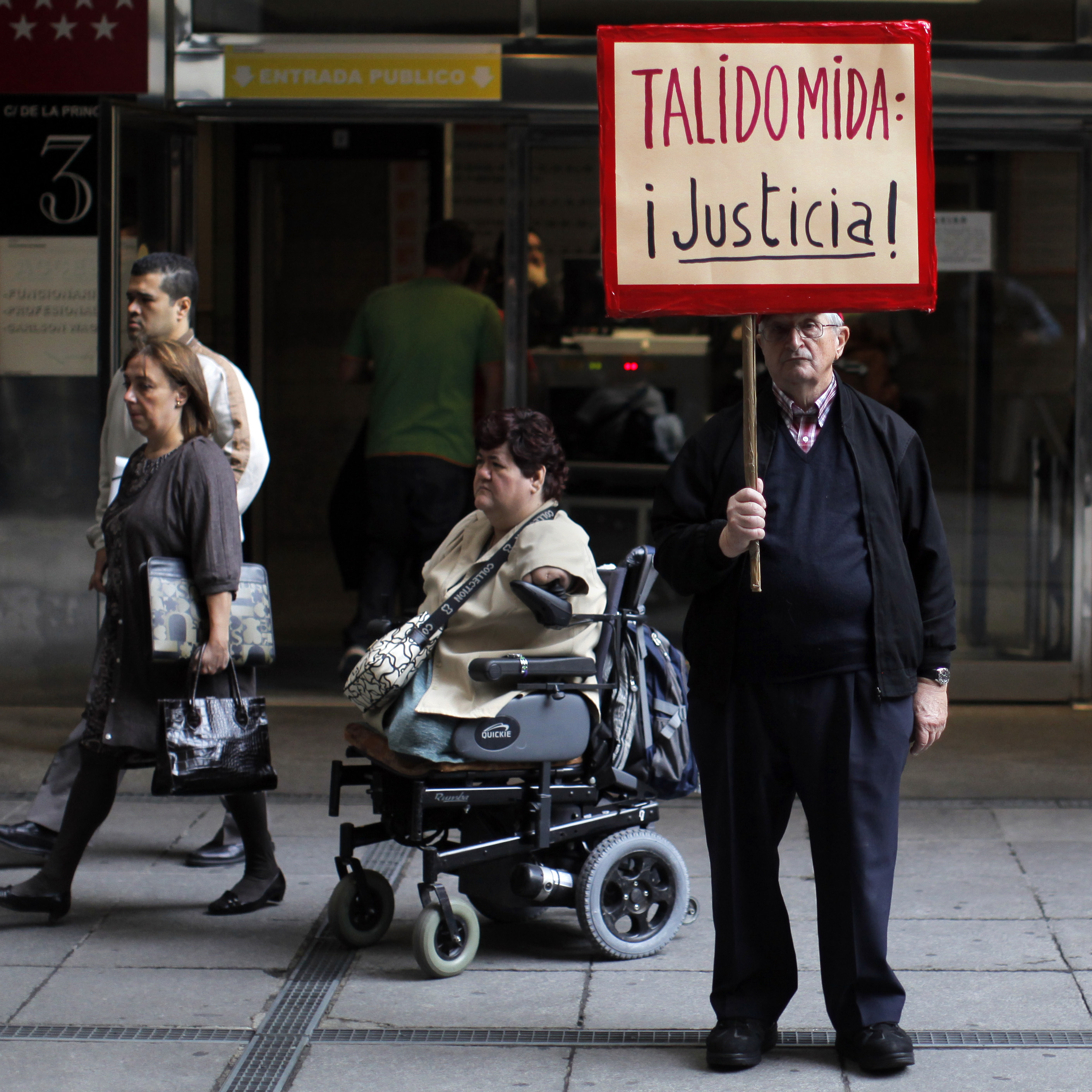 A Thalidomide victim leaves a Spanish court in a wheelchair while a protestor holds a sign reading "Thalidomide, Justice!" during a trial in Madrid in October 2013. Thousands of babies across Europe were born with abnormalities including missing limbs when expectant mothers were prescribed thalidomide in the 1950s and later.