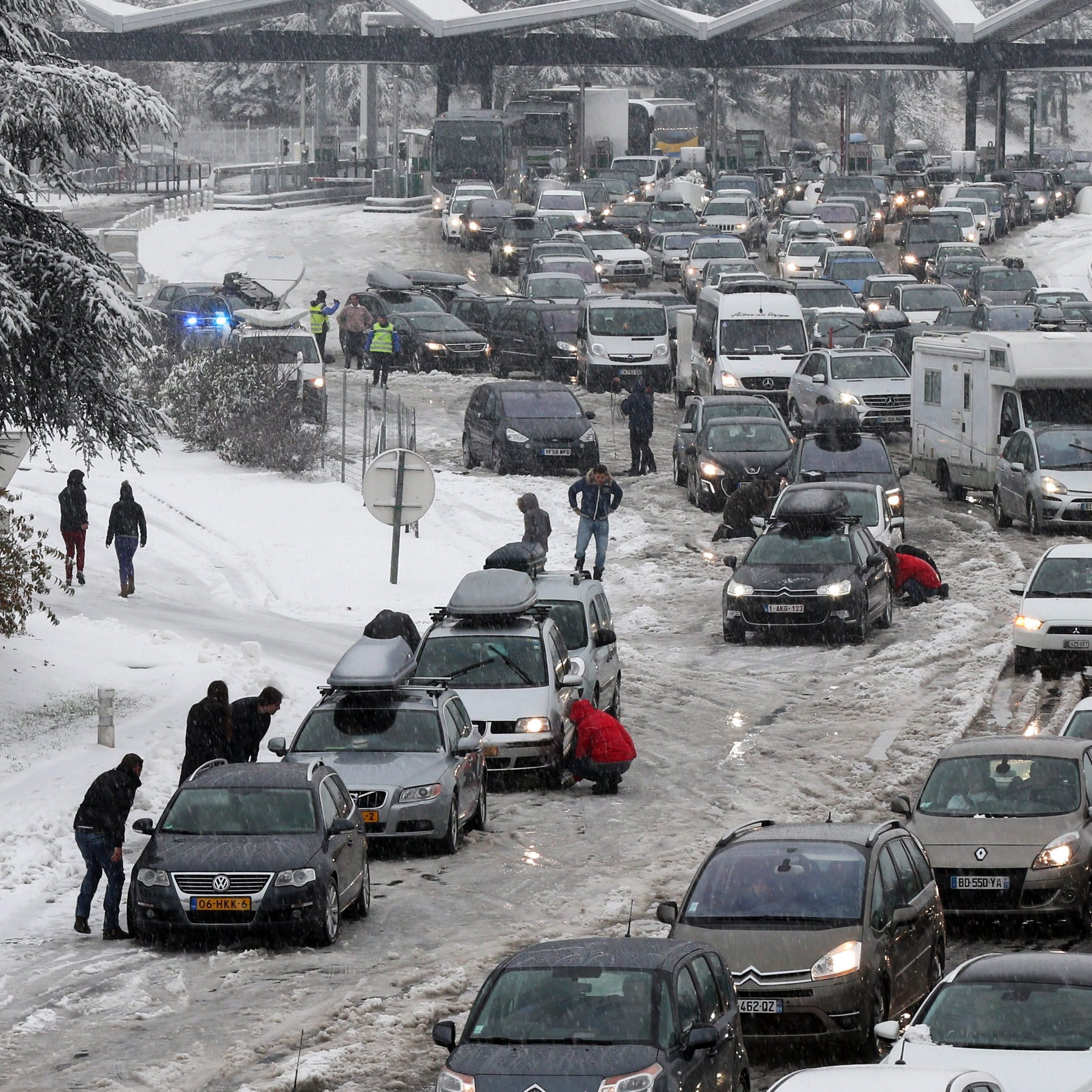 Drivers park to put on snow chains in the middle of a massive traffic jam in the Savoie region of France. Thousands of motorists are stranded for a second day.