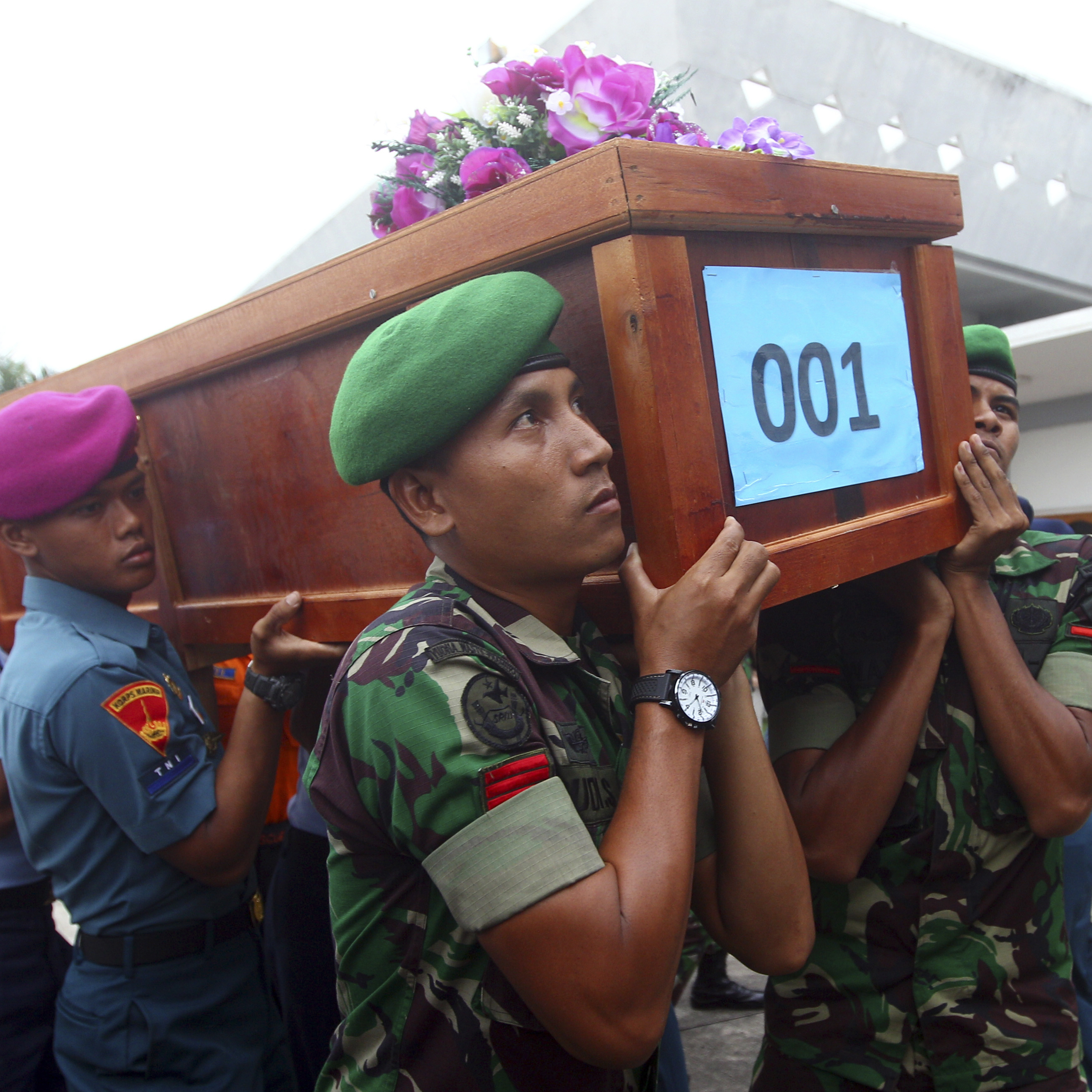 Indonesian soldiers carry a coffin containing a victim of AirAsia Flight 8501 upon arrival at Indonesian Military Air Force base in Surabaya, Indonesia, on Wednesday.