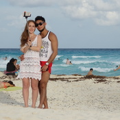 A couple uses a selfie stick on a Mexican beach.