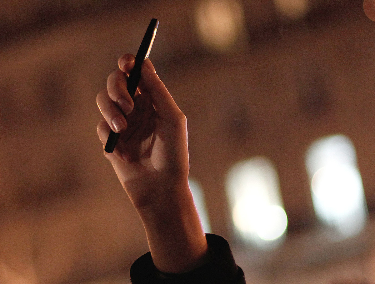 In Paris late Wednesday, a woman held a pen in the air during a memorial. Hundreds gathered to show solidarity with the cartoonists at Charlie Hebdo, where gunmen killed 12 people.