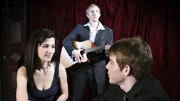 Jeez, people. The guy with the acoustic guitar is trying to perform right behind you. Get a room, would you? (iStockphoto.com)