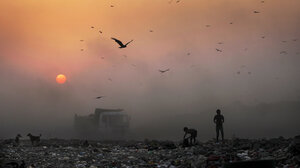 Smoke blankets the setting sun as young ragpickers search for reusable material at a garbage dump in New Delhi, India.