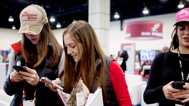 Dalia Wrochesinsky (left) and Robin Saidenberg check their phones during the Conservative Political Action Conference on Thursday. (NPR)