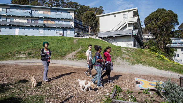 Uzuri Pease-Greene, right, leads a walk through the public housing complex in the Potrero Hill neighborhood of San Francisco where her family lives. She is working to have the old buildings replaced. (Talia Herman for NPR)