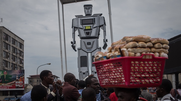 A man walks by with a basket of bread during the official presentation ceremony of three new robots that were installed in Kinshasa, Democratic Republic of Congo, on Tuesday to help tackle the city's traffic. (AFP/Getty Images)
