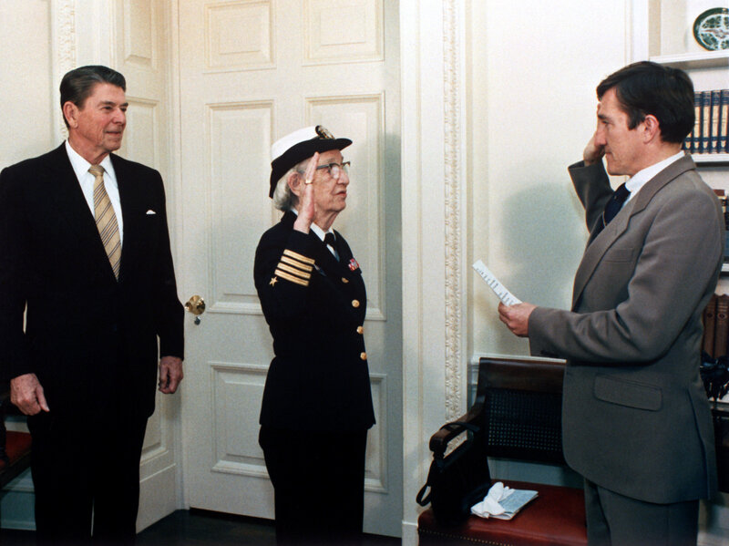 Secretary of the Navy John Lehman (right) promotes Grace Hopper to the rank of commodore in a ceremony at the White House with President Ronald Reagan.