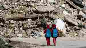 Girls carrying school bags provided by UNICEF walk past destroyed buildings on their way home from school on March 7 in the rebel-held al-Shaar neighborhood of Aleppo, Syria. So many people have fled the city and so much of its infrastructure has been destroyed that nighttime satellite images show 97 percent less light there compared with four years ago.