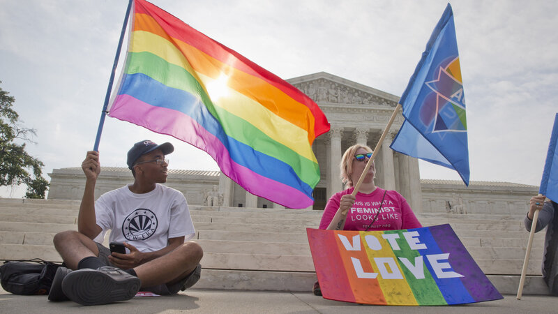 Carlos McKnight (left), and Katherine Nicole Struck hold flags in support of gay marriage outside of the Supreme Court on Friday.