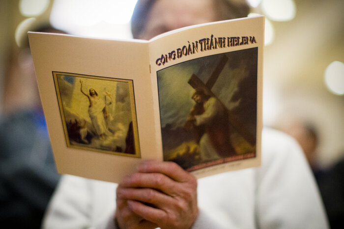 In this photo from April 3, Good Friday, a Vietnamese-American woman at St. Helena Church in Philadelphia sings while holding a program printed in Vietnamese.  (Matt Rourke/AP)