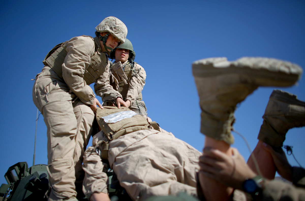 Marine Lance Cpls. Julia Carroll (left) and Paula Pineda lift "Carl" — a 220-pound test dummy — during training in March in California. Female Marines have completed months of training and are now waiting to hear whether they will be allowed to serve in combat roles.